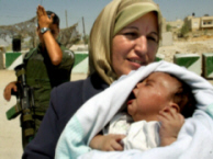 Beit Sahour 115, August 4, 2003, Photo above: A Shout, Photo by: Nayef Hashlamoun.   A Palestinian baby cries under a hot sun while his mother tries to pass back home in front of an Israeli soldier (back) covering his face at an Israeli checkpoint of Wadi al-Nar near of the West Bank city of Beit Sahour. Israeli army blocked the roads around the Palestinian cities south of Jerusalem for the Palestinian control.